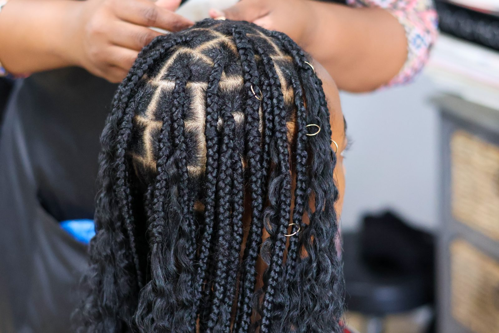 Child's braided hairstyle with beige and black cornrows and decorative hair rings