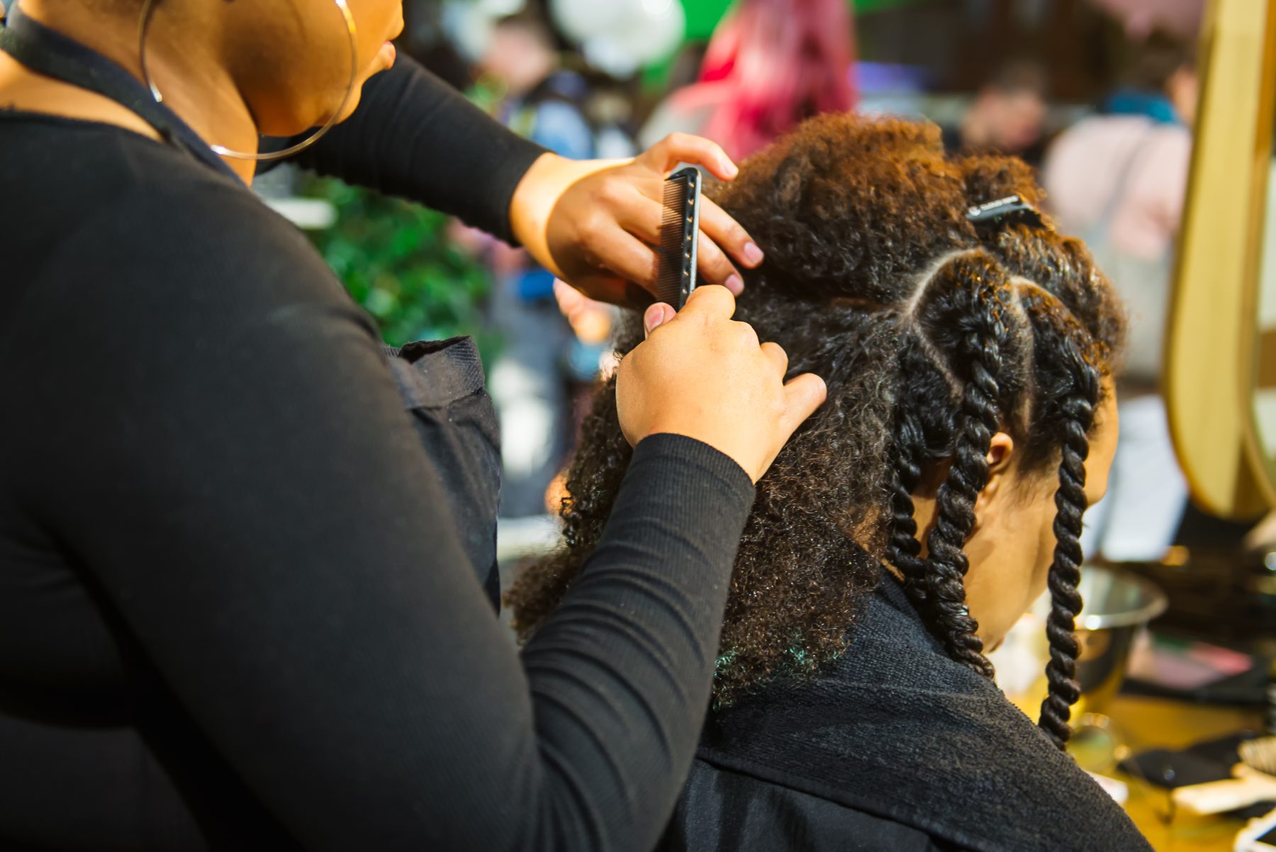 Barber styling client's braided hair with comb in salon setting